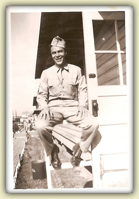 Warren in army garb, smiling, sitting on a porch railing
